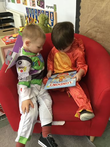 A photo of Hundred of Hoo Nursery pupils wearing their fancy dress outfits for World Book Day 2022 and reading a book.