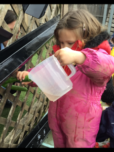 Photo of Nursery pupils playing with water outdoors.